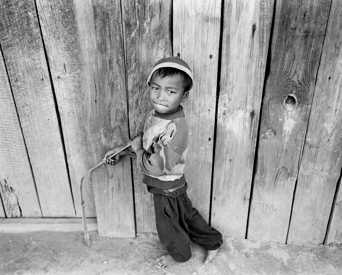 boy holding bamboo against house.jpg